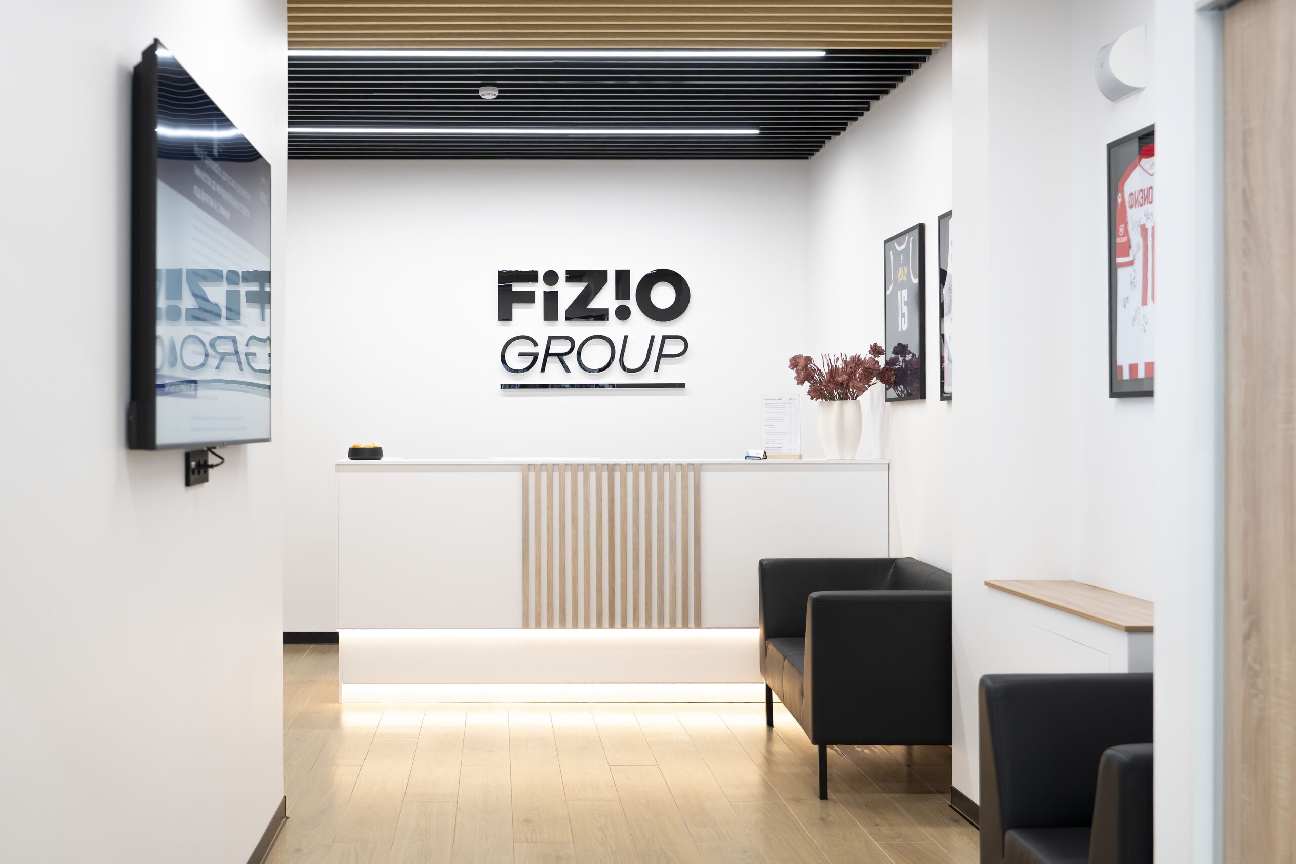 Зона ожидания у стойки администратора с логотипом FIZIO GROUP
